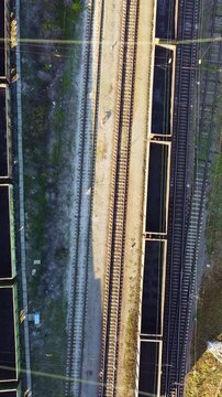 Vertical aerial view of empty freight train moving on railway track. Rail transport systems, infrastructure engineering, modern railway network organization