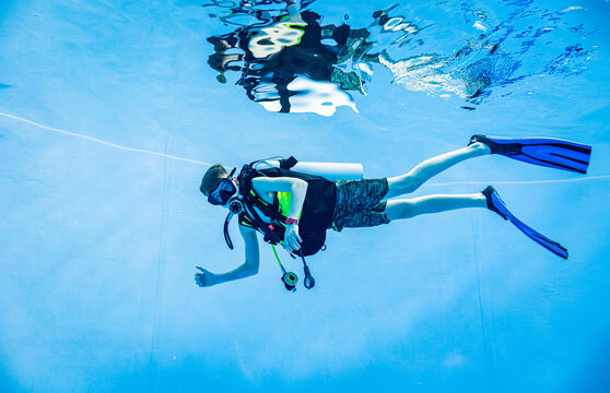 Scuba diver descending in a deep blue swimming pool
