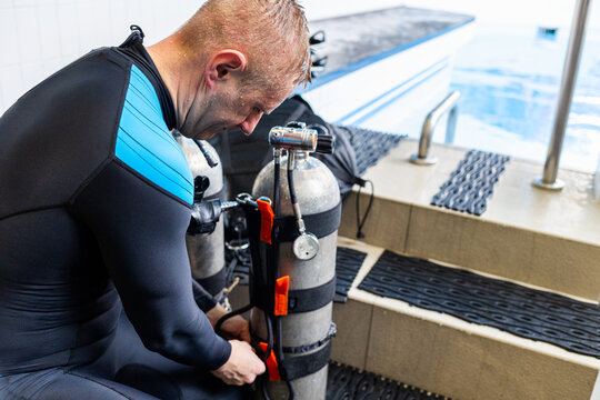 Close-up of a scuba diver preparing air cylinders at an indoor training pool