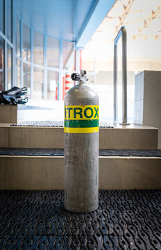 Close-up of a Nitrox scuba tank standing on the steps of an indoor training pool