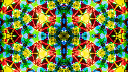 Fototapeta premium Seamless pattern of a real kaleidoscope ornament captured with a camera lens. A vibrant, natural symmetrical texture with colorful glass shapes, perfect for backgrounds, textiles, wallpaper, printing,