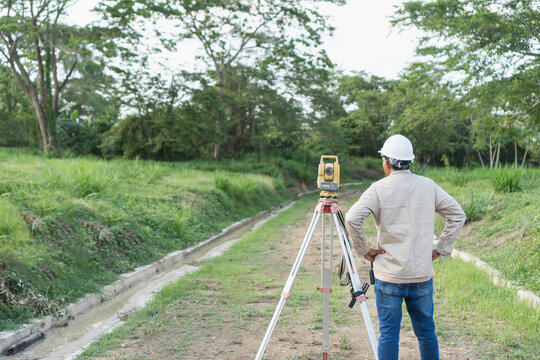 Surveyor using total station for topographic land measurement
