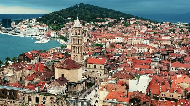 Cinematic aerial drone footage of Split featuring the Adriatic coastline, historic old town, marina, and Mediterranean atmosphere. Ancient architecture mixed with modern coastal life