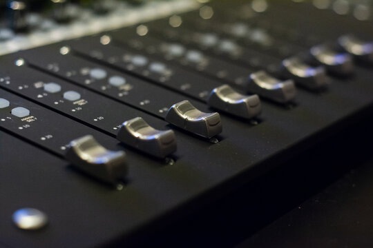 Close-up Selective Focus of Faders and Knobs on a Professional Mixing Console in a Recording Studio
