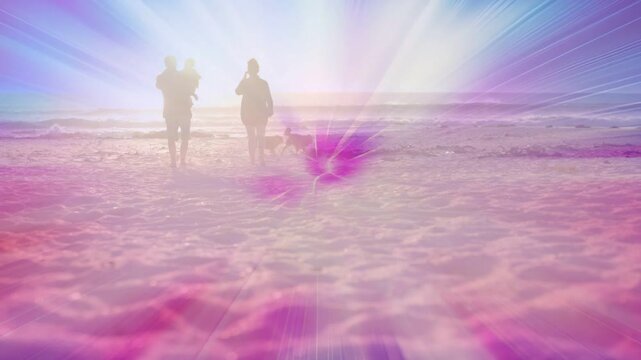 Family walking toward camera shore man holding baby dog sun casting pink overlay for sunset travel