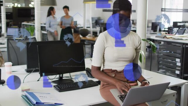 Seated woman typing on laptop and activating blue charts overlaying open office for analytics