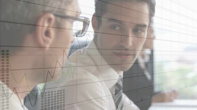 Two execs reviewing funds at table by window, right exec speaking gesturing causing charts updating