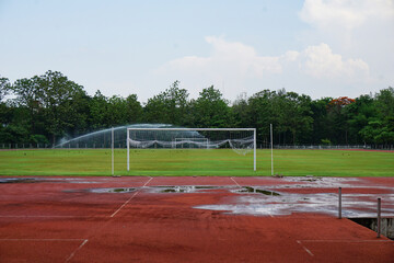 Fototapeta premium Empty football stadium with wet running track and green lawn maintenance.