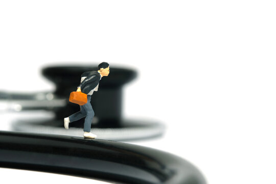 Miniature people toy figure photography. A boy pupil student running above stethoscope. Isolated on white background
