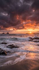 Obraz premium Dramatic Ocean Sunset with Crashing Waves Rocky Beach and Stormy Sky Landscape Wallpaper