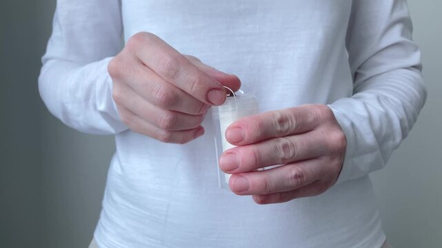 Woman takes dental floss out of the box and tears it off in a special place. Importance of comprehensive hygiene, including not only brushing teeth, but also thorough cleaning of interdental spaces