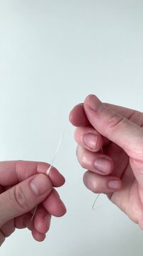 Vertical video. A woman wraps dental floss around her fingers. Gum disease, gingivitis. The importance of regular interdental cleaning to protect the gums, prevent inflammation and bleeding