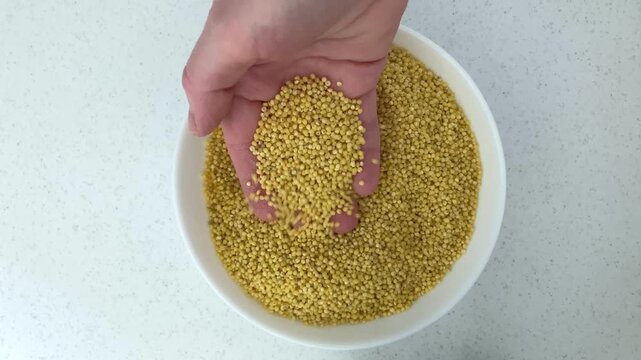 The woman gently picks through the millet, pleasant tactile sensations, simple everyday actions. An atmosphere of peace, harmony and comfort, inner peace and relaxation. Close up, top view