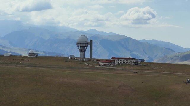 aerial view of the Assy-Turgen Observatorium in Kazachstan, a soviet era space telescope with horses running in the foreground