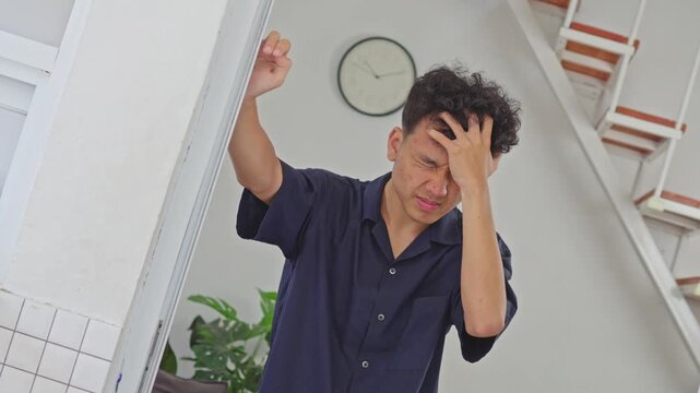 Camera tilts to simulate intense vertigo as young man clutches head in pain