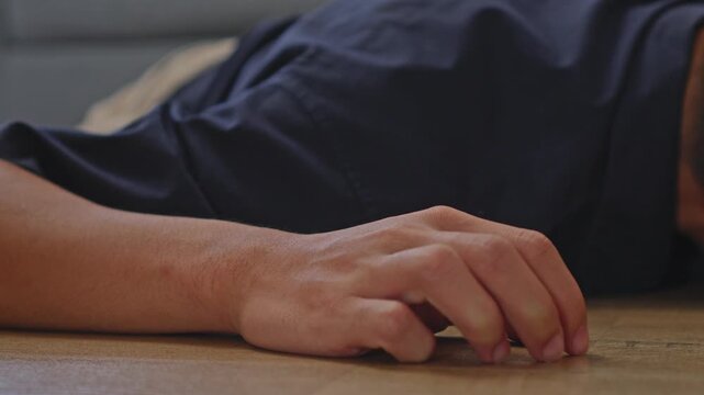 Close-up of hand resting helplessly on ground as individual falls unconscious from severe vertigo
