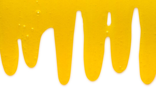 Yellow liquid transparent gel dripping down against white background.
