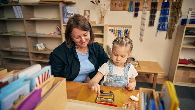Quiet child building pattern from natural objects during preschool sensory lesson. Concept of early development, tactile play, fine motor control, nature study, and childcare support.