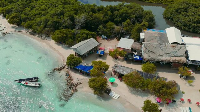 Drone aerial orbit of Isla Mucura at 45 degree angle showing beach commerce huts tropical forest and ocean horizon with smooth continuous movement
