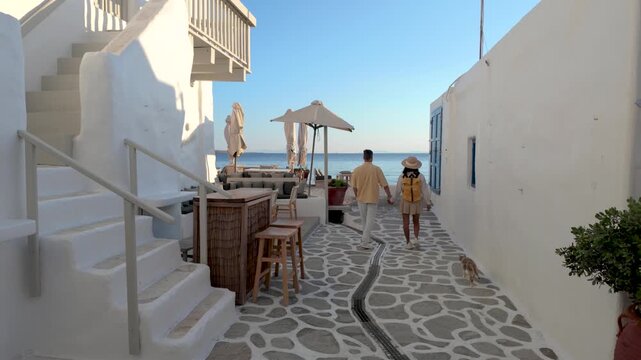 A diverse couple strolls through the enchanting alleys of Paros, Greece, where sunshine bathes the whitewashed buildings. Enjoy the vibrant atmosphere, beautiful views, and a sense of tranquility.