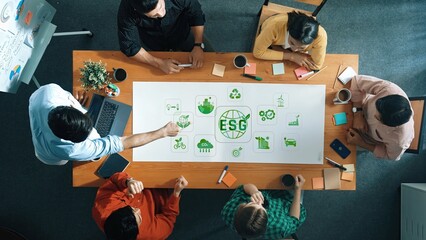 A diverse group of professionals collaborates on strategies related to environmental, social, and governance practices, discussing ideas and insights at a boardroom table. Raster