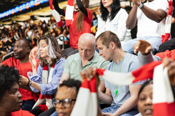 Fototapeta premium Football fans placing a risky bet ticket on in-play live gambling app, watching intense soccer match from the stadium stands. Enthusiasts follow sports betting odds during important game.