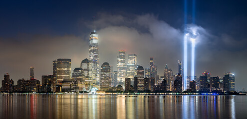 Dawn in Lower Manhattan with skyscrapers and low clouds and the September 11 Tribute in Light memorial lights. Financial District, New York City, USA © Francois Roux