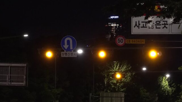 Korean traffic sign indicating high accident area next to a changing traffic signal and u-turn sign