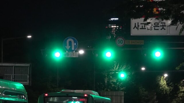 Korean traffic signal turning green as a city bus begins to drive under an accident warning sign