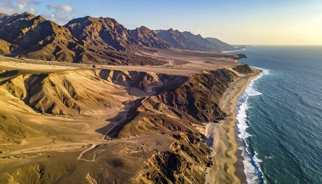 Desert landscape converges with ocean along a rugged coastal area, shore break at cliffs, blue cloudy sky at sunset, dry landscape in an aerial drone view, AI generated
