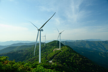 Wind Turbine Farm on a Forested Mountain Ridge at Golden Hour. Wind turbines generate clean renewable energy. © BananaShot