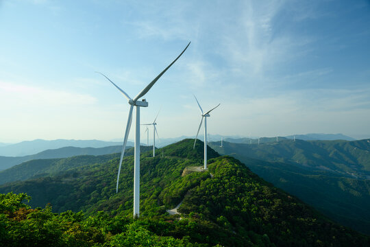 Wind Turbine Farm on a Forested Mountain Ridge at Golden Hour. Wind turbines generate clean renewable energy.