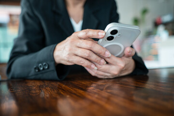 Fototapeta premium Close-up of businesswoman hands using and holding a smartphone at workplace.