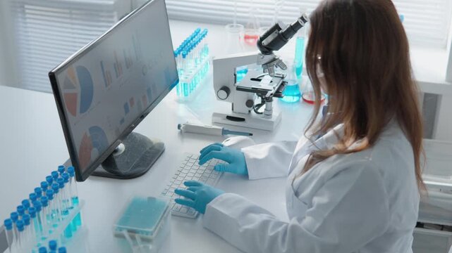 A woman researcher uses advanced laboratory equipment, including a microscope and computer, to study biological samples. The scene highlights innovation and technology in scientific research