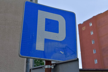 A blue public parking sign on a metal post with a red building in the background. Great for city parking rules, urban infrastructure, and traffic regulation concepts  © Яна Руднева