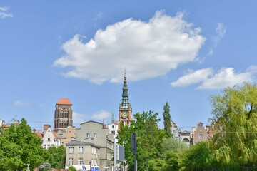 Panoramic view of a European old town skyline with historic church spires and green trees under a bright blue sky with clouds. Perfect for travel tourism and history concepts  © Яна Руднева