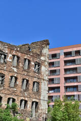 Obraz premium Ruins of an old red brick building standing next to a modern residential apartment house. Contrast of historical and contemporary urban architecture. 