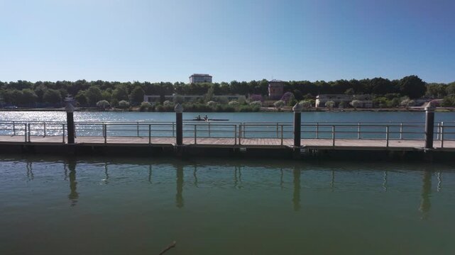 Rowing on a Sunny Day in Seville: A Calm River Scene with a Wooden Dock and Scull Boat