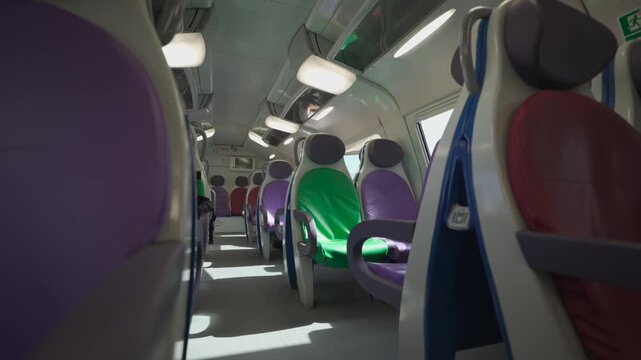 Empty cabin of a modern Trenitalia double-decker train en route to Rome airport. Interior view of public Italian railway transport with bright colorful seats stock video.