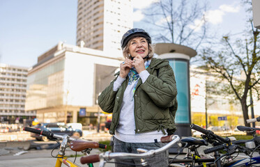 Fototapeta premium Senior woman wearing helmet while riding bicycle in the city 