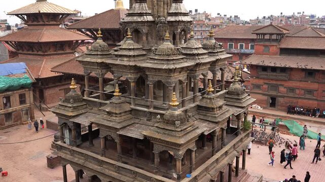 Kathmandu, Nepal - 19 May 2026: View of the historic Krishna Mandir temple and surrounding pagoda architecture in Patan Durbar Square with people walking below.