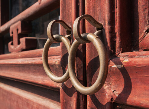 Old door handles on a wooden door with weathered paint in a sunny location