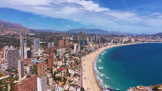Panoramic view of Benidorm, Spain showing the iconic skyline of high-rise buildings along Levante Beach with turquoise Mediterranean Sea and mountain backdrop