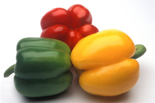 green, red and yellow capsicums in a studio shot setting with white background