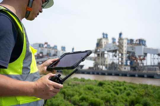 Engineer holding tablet and remote controller to inspect industrial factory site