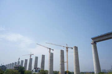 Fototapeta premium Construction site of bridge piers with cranes under blue sky