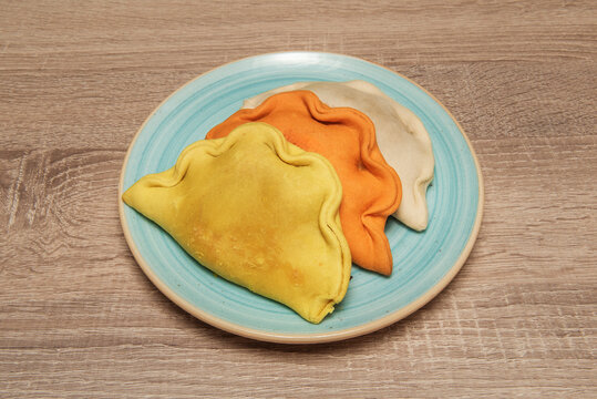 Tuna and tomato empanadas, the dough orange from the concentrated tomato filling, served with lemon.