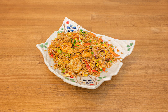 A close-up of Cantonese fried rice with generous pieces of char siu (roasted pork), baby prawns, peas, sweetcorn, and fresh spring onions, all with the characteristic golden color of soy sauce