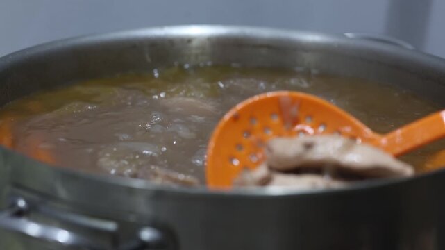 Professional chef preparing a hearty beef stew, skimming scum from the boiling broth with a skimmer