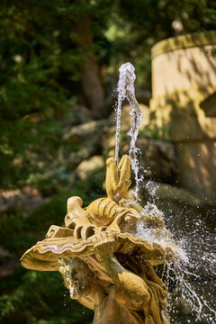 Stone fountain statue with water splash in sunlit garden
